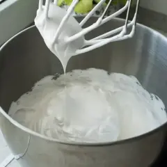 Ubita śmietana z mascarpone, puszysta i idealna do deserów, właśnie powstaje w metalowej misie miksera.