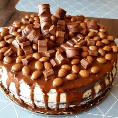 Pyszny tort kinder obficie udekorowany batonikami i czekoladowymi kuleczkami.