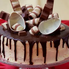 Pyszny tort kinder bueno z polewą czekoladową i dekoracjami z batoników i jajeczek.