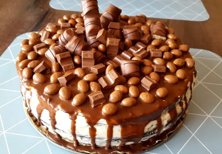 Pyszny tort kinder obficie udekorowany batonikami i czekoladowymi kuleczkami.
