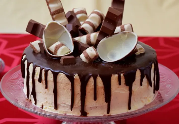 Pyszny tort kinder bueno z polewą czekoladową i dekoracjami z batoników i jajeczek.