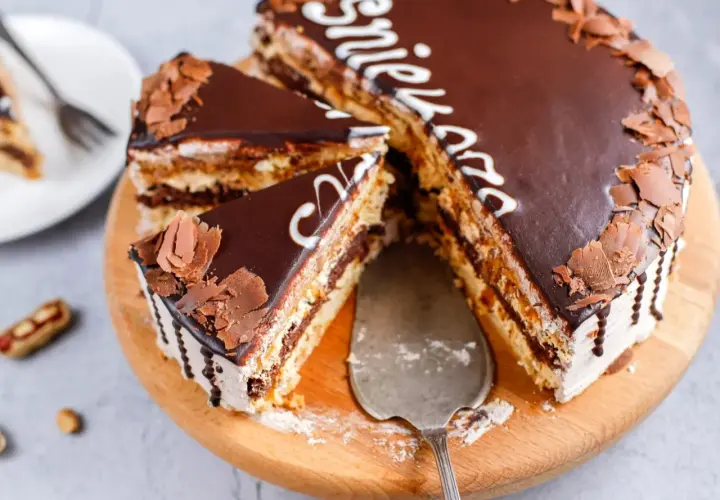 Pyszny tort snickers z czekoladą i orzeszkami, pokrojony na kawałki, gotowy do podania.