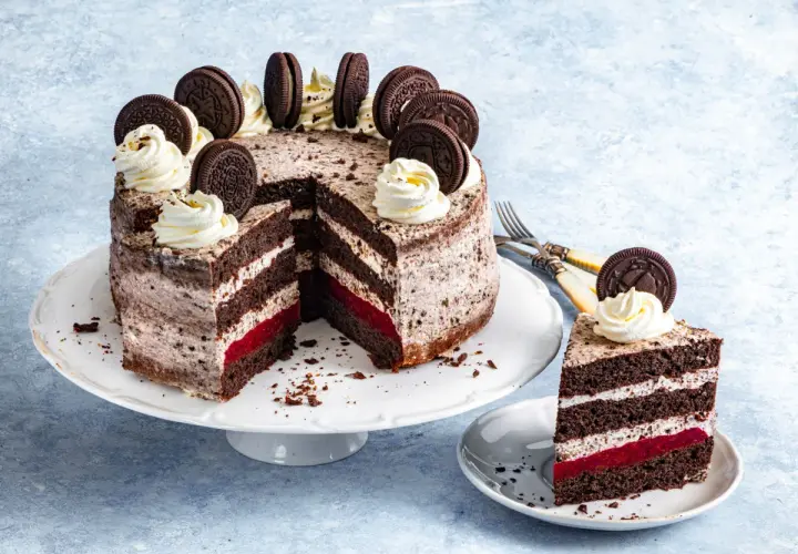 Pyszny tort z kremem oreo i malinami, ozdobiony ciasteczkami i bitą śmietaną. Idealny na każdą okazję.