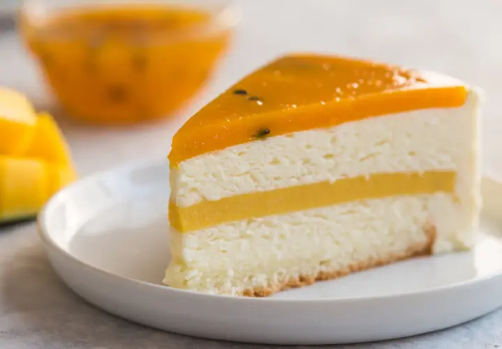 Pyszny tort mango z warstwami musu i galaretki, ozdobiony owocami. Idealny deser dla miłośników tropikalnych smaków.